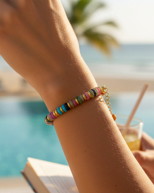 Multicolored beaded bracelet with gold chain on a white background