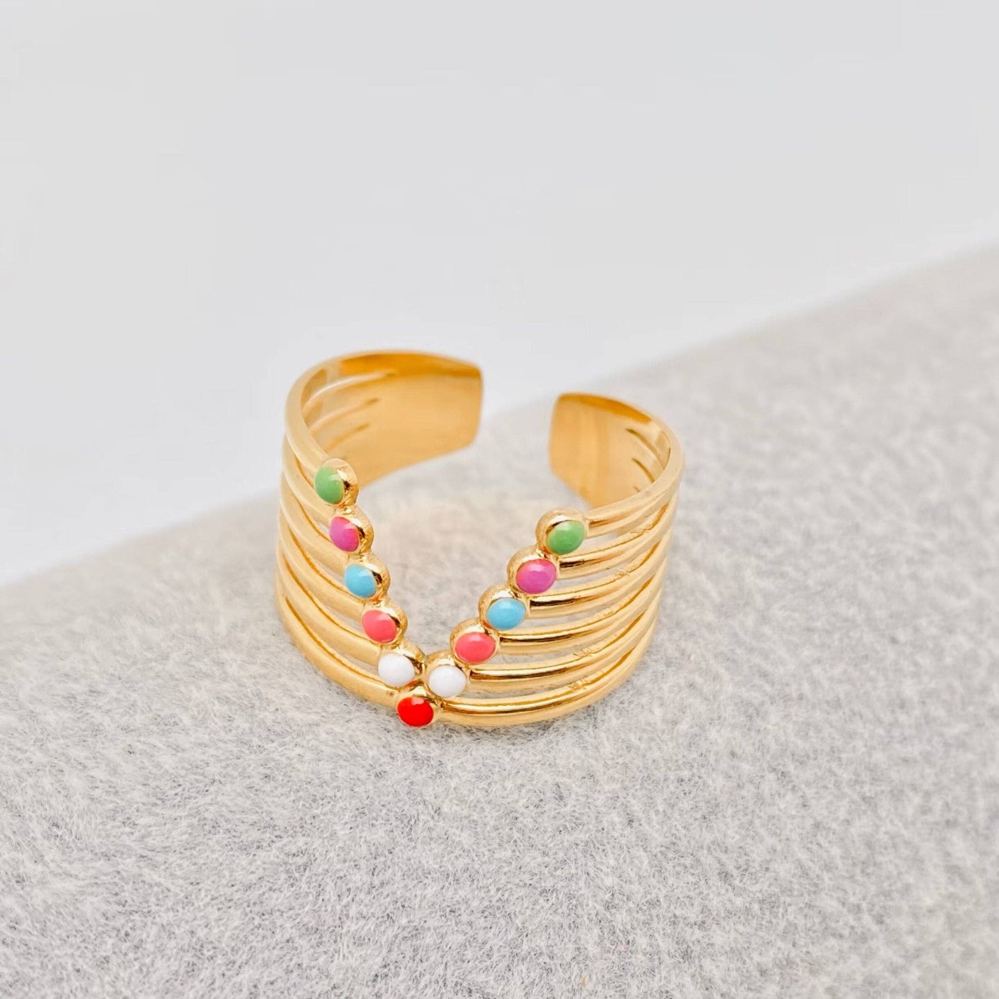 Gold adjustable ring with colorful enamel dots on a gray surface