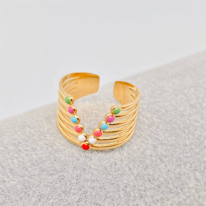 Gold adjustable ring with colorful enamel dots on a gray surface