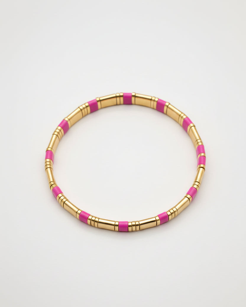 Gold and pink beaded bracelet on a gray background
