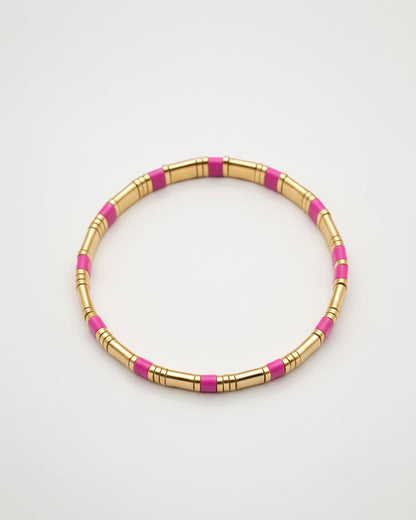 Gold and pink beaded bracelet on a gray background