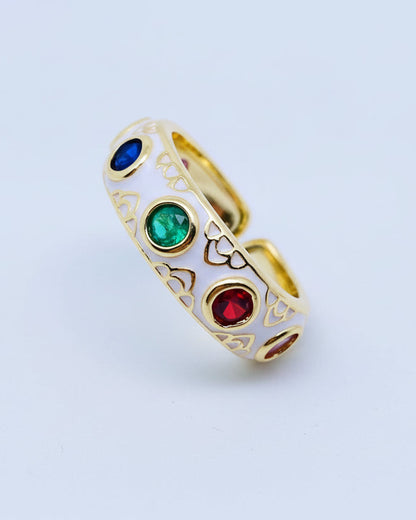 Gold ring with colored gemstones on a white stand