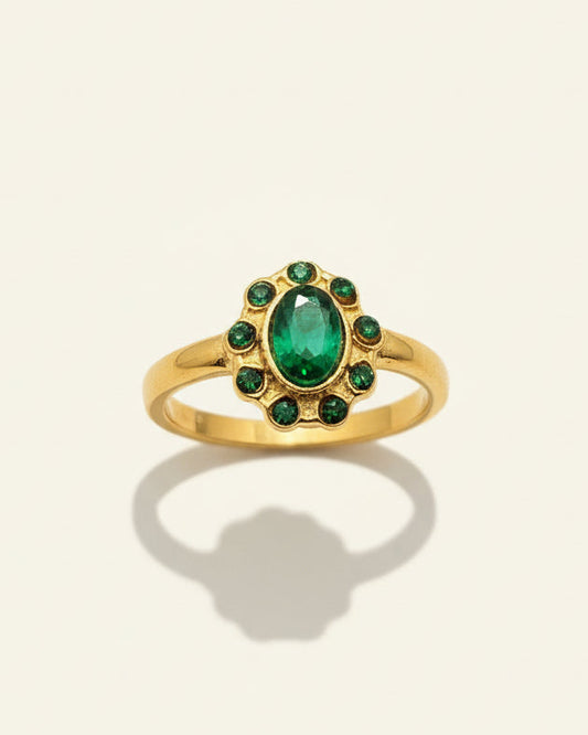 Gold ring with emerald stones on a beige background