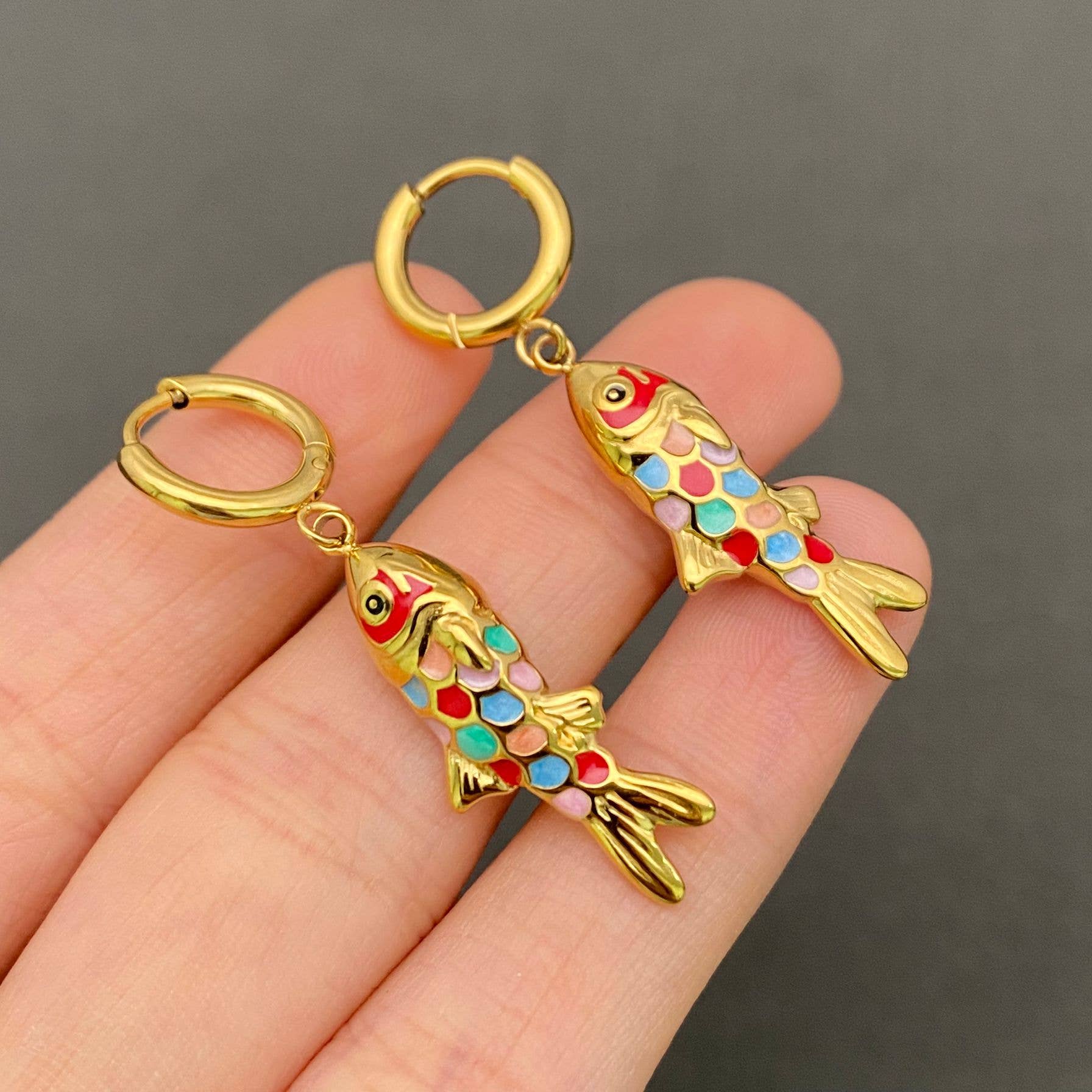 Close up of playful fish design huggie hoop earrings with enamel detail