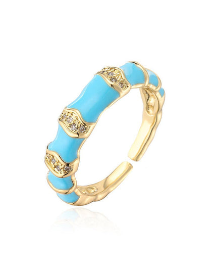 Turquoise blue enamel ring with cubic zirconia stones and gold plating on white background