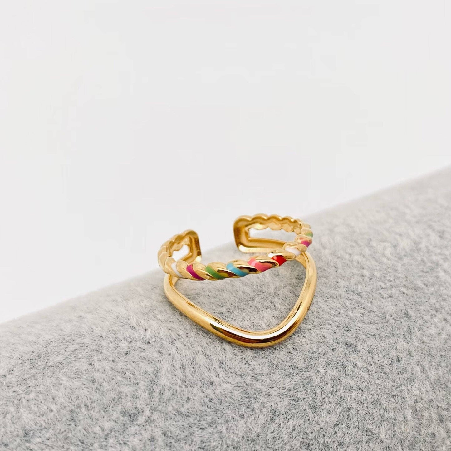 Gold ring with colorful enamel dots on a gray surface