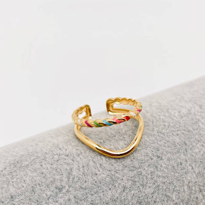 Gold ring with colorful enamel dots on a gray surface