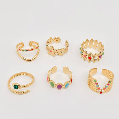 Set of gold rings with colorful gemstones on a light gray background