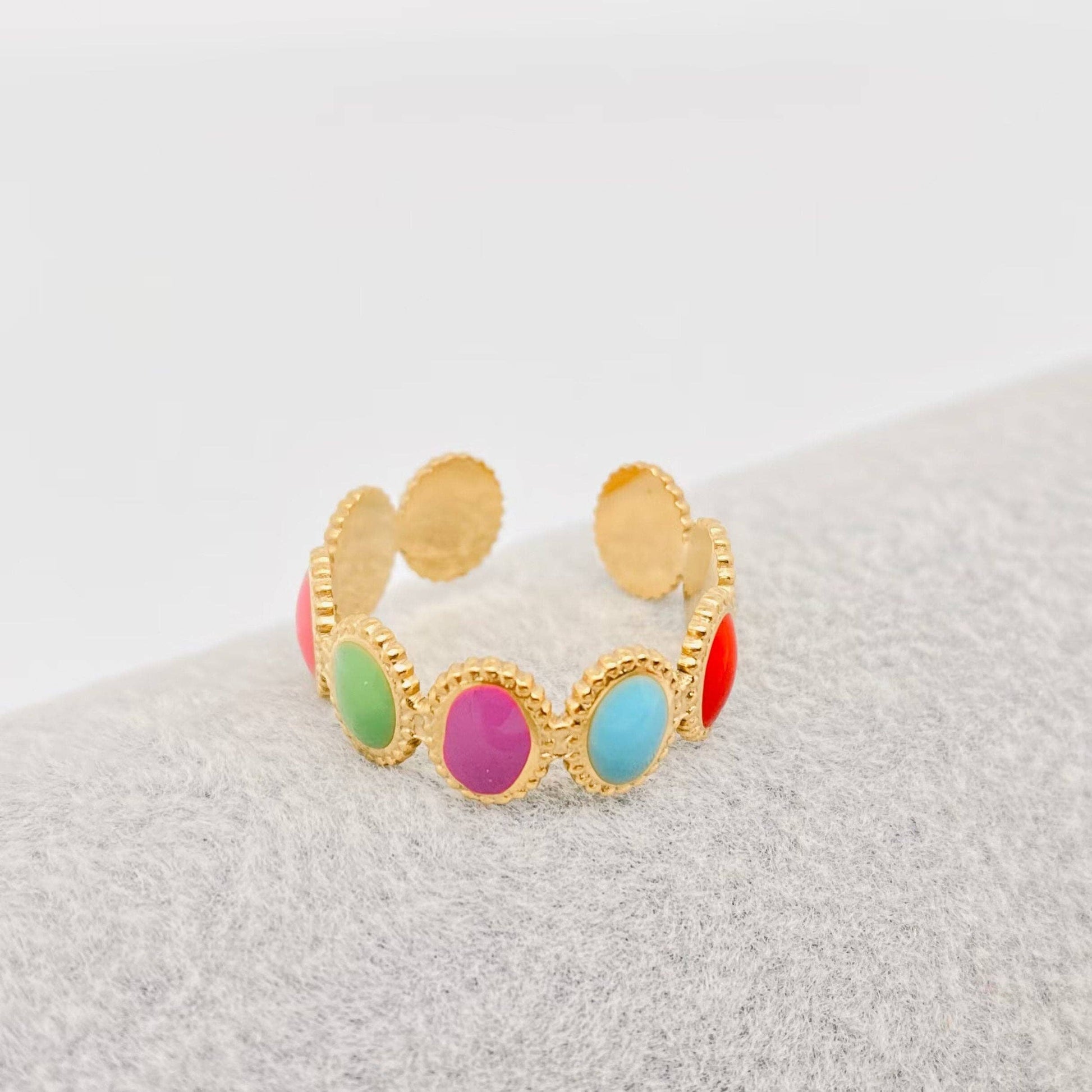 Gold ring with colorful enamel dots on a textured surface