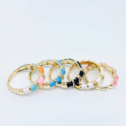 Set of gold bangles with colorful accents on a light gray background