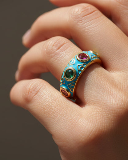 Gold  and blue enamel ring with colorful gemstones on a white background