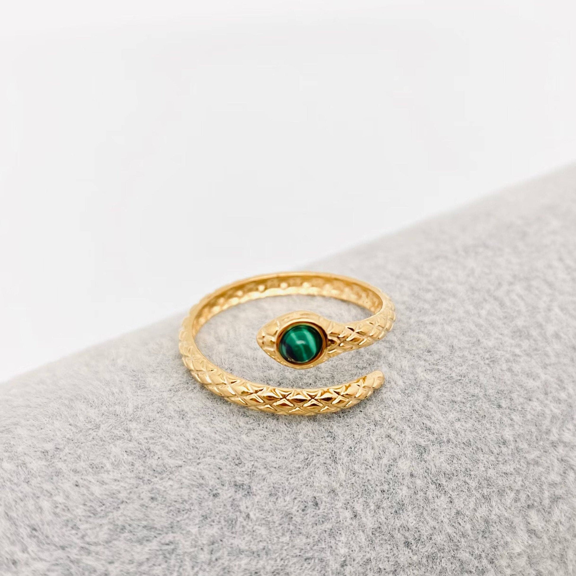 Gold ring with a green gemstone on a gray surface