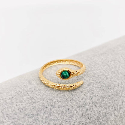Gold ring with a green gemstone on a gray surface