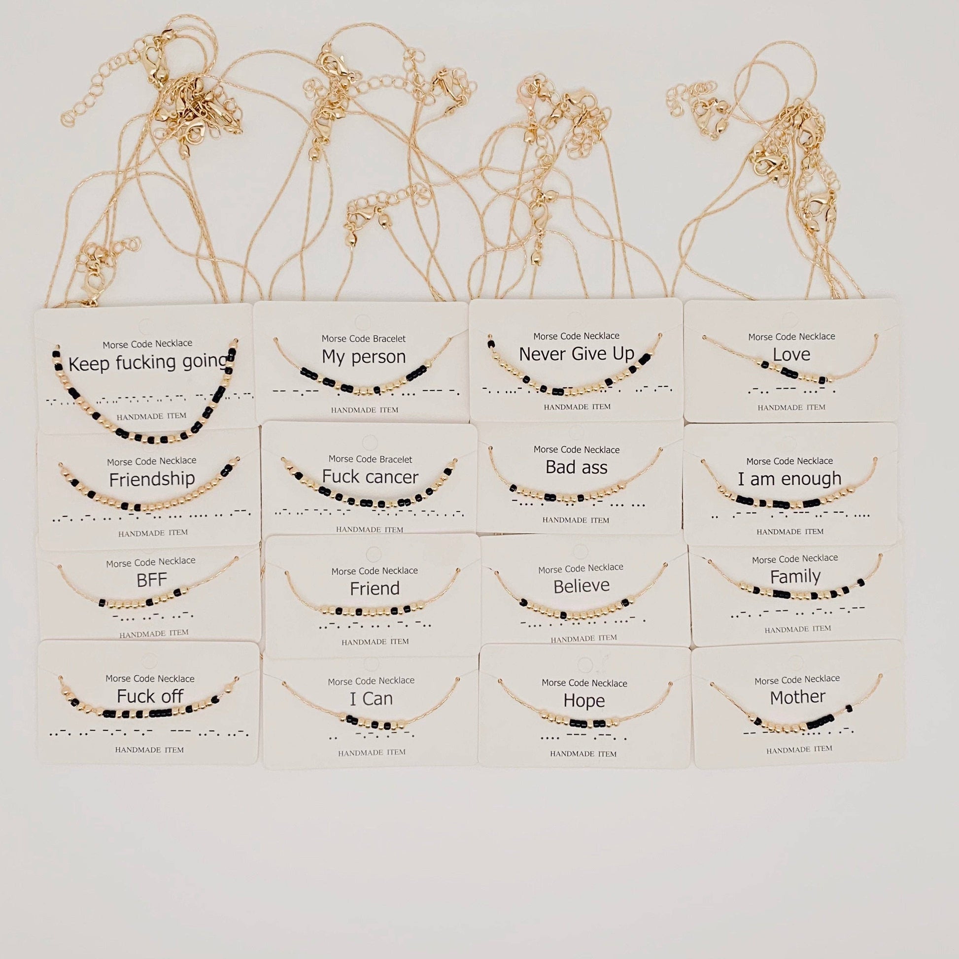 Collection of gold necklaces with various morese code messages on white boxes