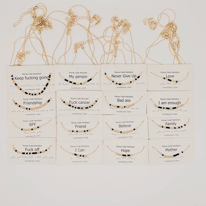 Collection of gold necklaces with various morese code messages on white boxes