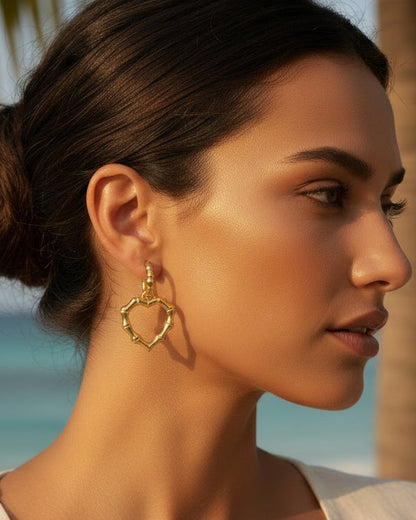 Gold heart-shaped hoop earrings on a light gray background