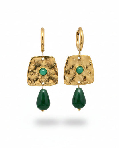 Gold earrings with green gemstones on a gray background