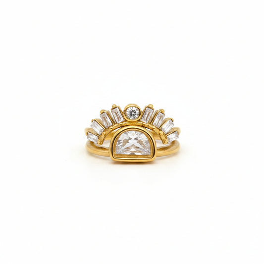 Gold ring with a large central diamond and smaller diamonds on a finger against a gray background
