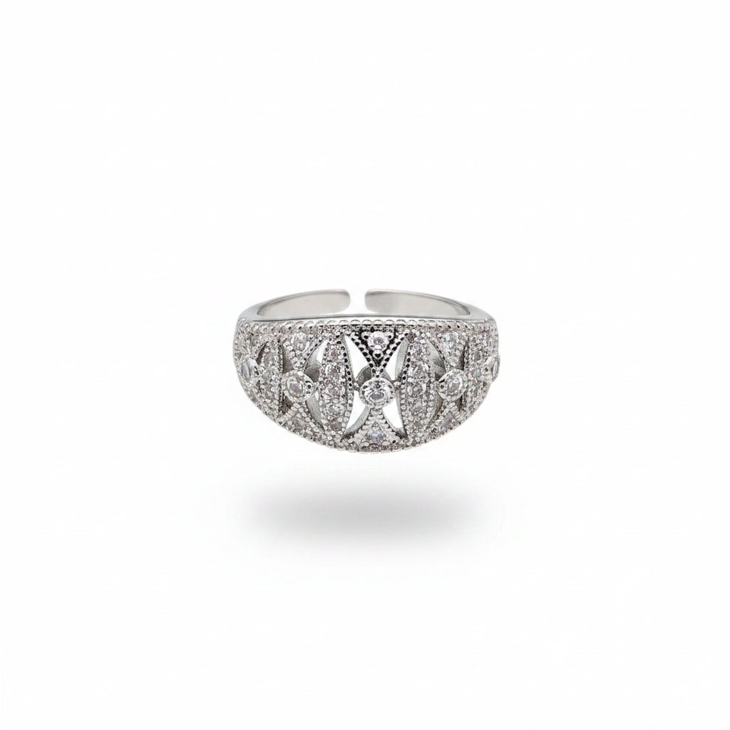 A silver-toned filigree ring with clear stones, shown resting on a person's fingers against a dark gray background.