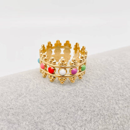 Gold ring with colorful beads on a textured surface