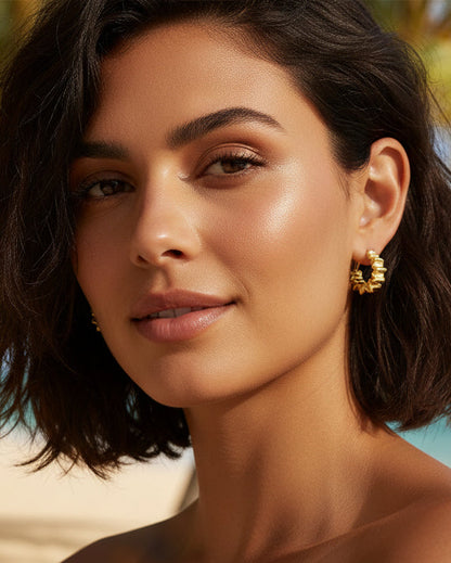 Woman wearing gold wiggly striped small hoop earrings showing 1.5cm size